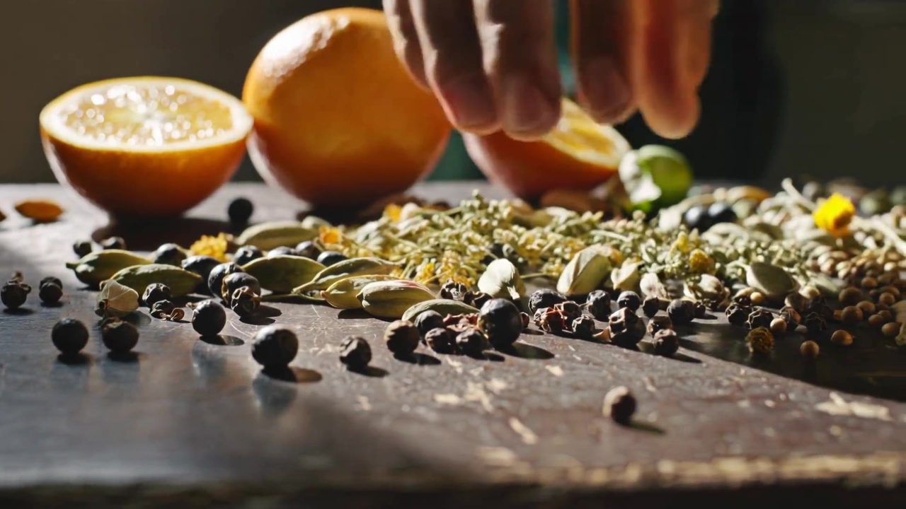 A hand setting out Nagpur orange, juniper and whole spices on a worn wooden table